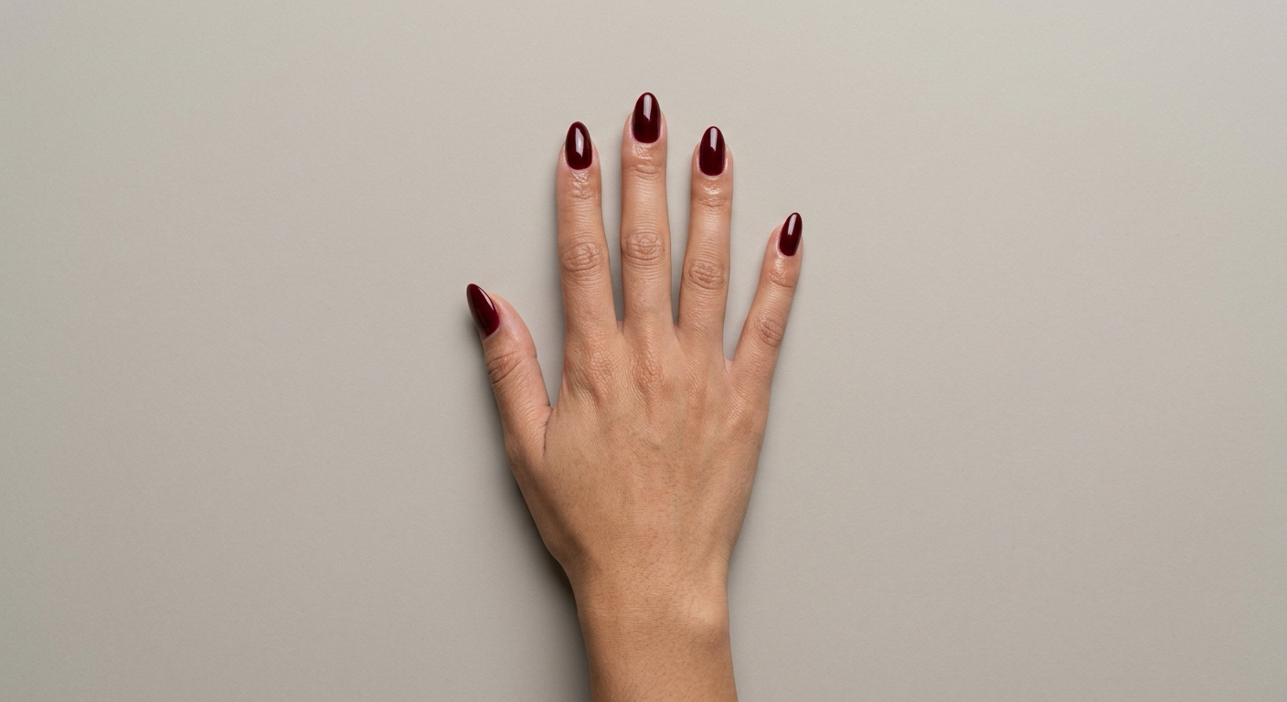 A hand wearing Cherry Cola Glaze, a deep bordeaux gel